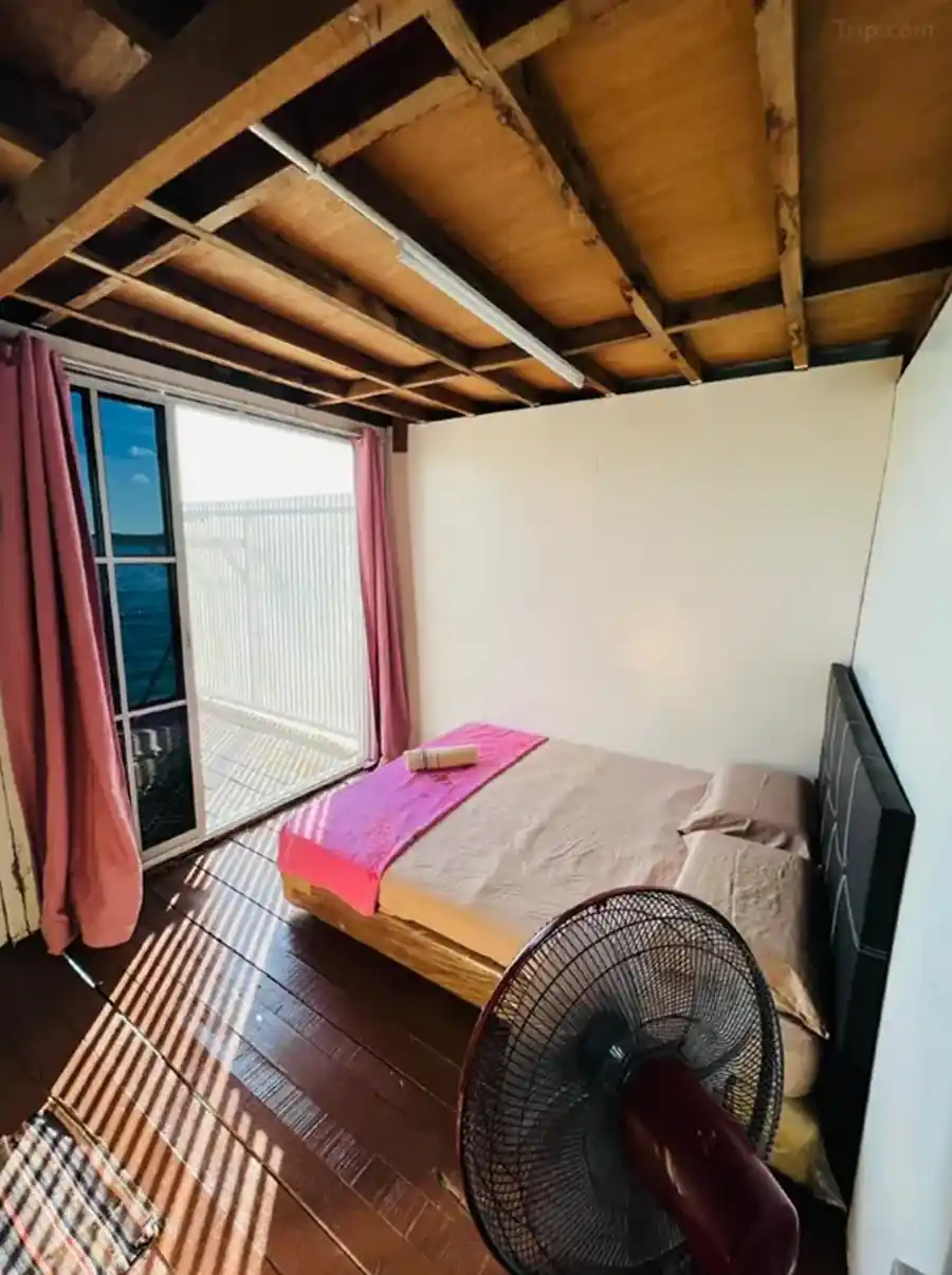 Cozy Queen Room at Egang Egang Resort featuring a comfortable bed, wooden floors, and sliding doors opening to a private sea view balcony.