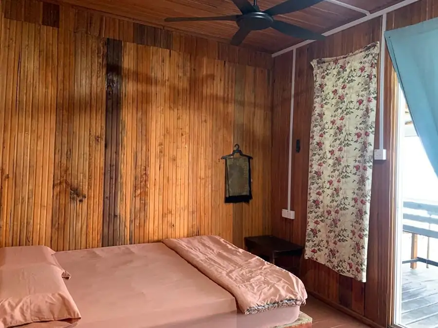 Rustic interior of the Queen Room at Egang Egang Resort featuring natural wood paneling and a comfortable bed.