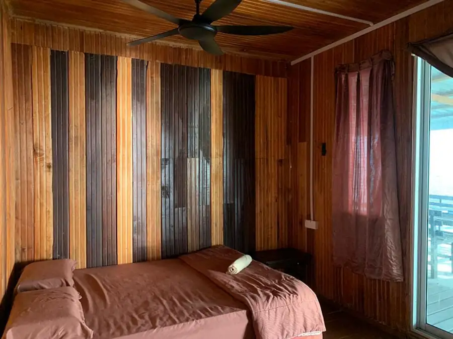 Comfortable Queen Room at Egang Egang Resort featuring unique vertical wooden wall panels and a ceiling fan.