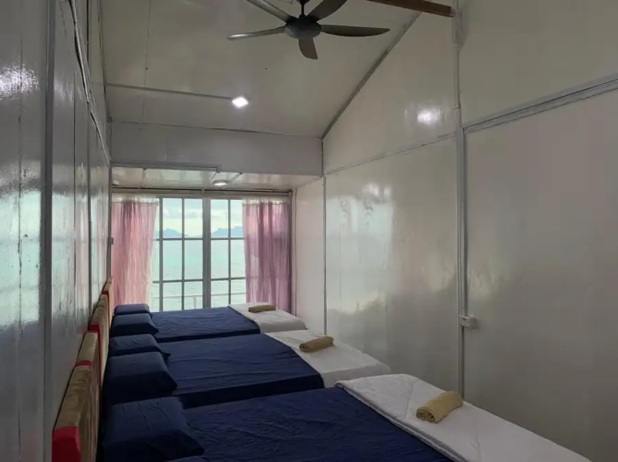 Clean and simple interior of the Triple Room at Egang Egang Resort showing multiple beds and an ocean view.