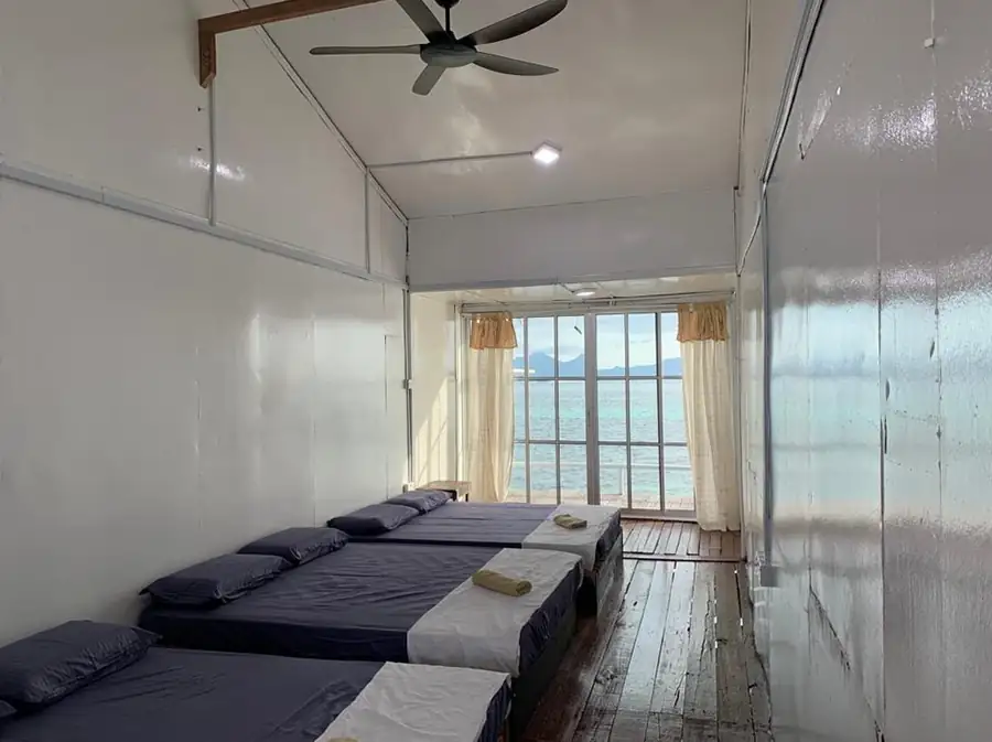 Spacious Triple Room at Egang Egang Resort with multiple beds and sliding glass doors opening to the beautiful ocean.